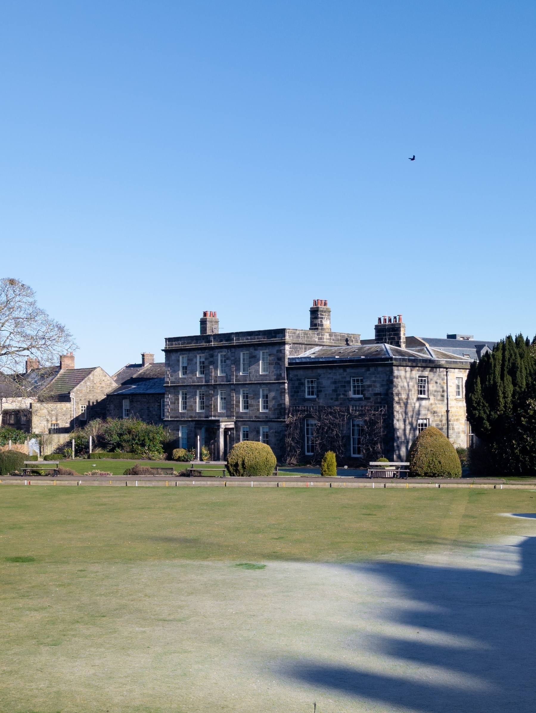 Old house by the cathedral. Bowling green lawn in front with morning shadows and frost
